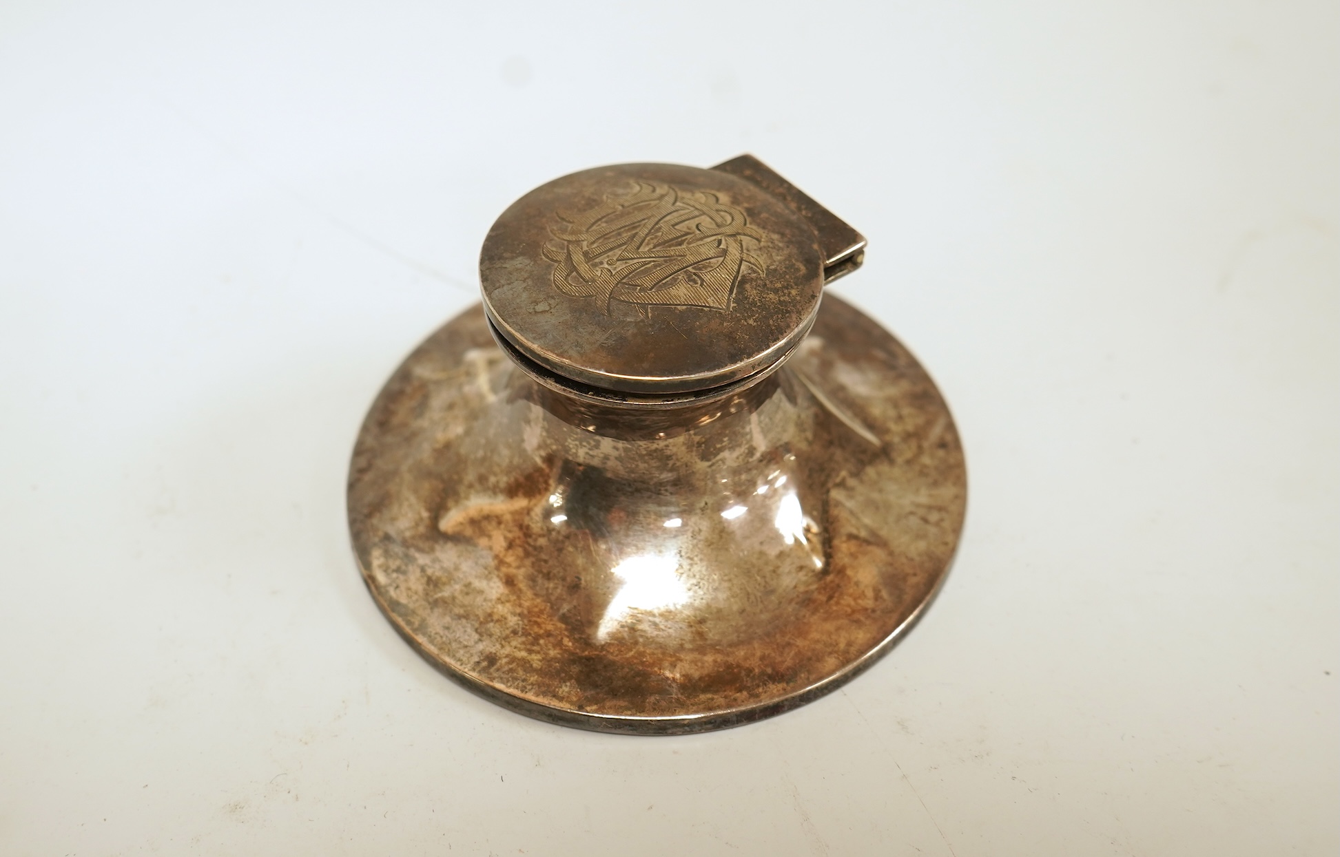 A small silver mounted capstan inkwell, a set of four George V engine turned silver napkin rings and a silver handled magnifying glass.